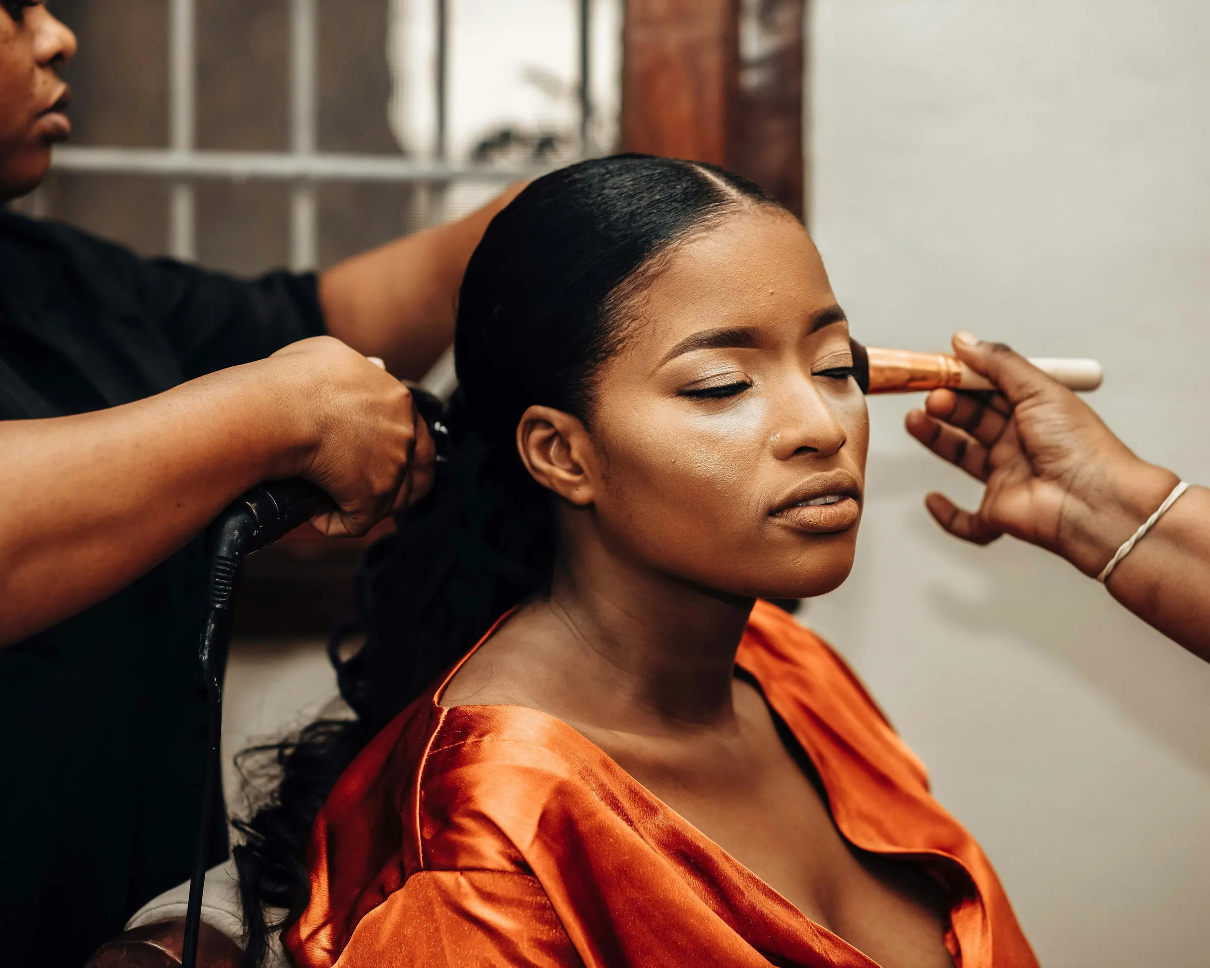 Maquilleuse et coiffeuse qui préparent une cliente en salon